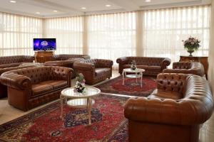 a living room with brown leather couches and a tv at Hotel Gaston in Rimini