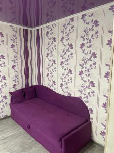 ヘルソンにあるRed Apartment 2019 Very Centreの壁に花が飾られた部屋の紫色のソファ