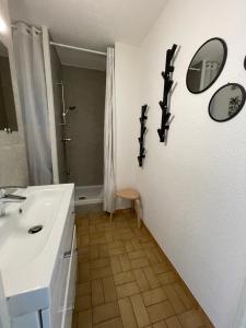 een badkamer met een wastafel, een douche en spiegels bij Studio le couchant in La Grande-Motte