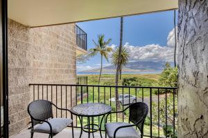 a balcony with a table and chairs and a view at Kauhale Makai in Kihei