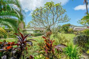 un jardin avec des plantes tropicales et une maison en arrière-plan dans l'établissement Puamana 6B, à Princeville