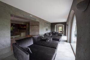 a living room with black leather couches at Gartenhotel Völser Hof - Adults Only in Völs am Schlern