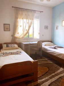 1 Schlafzimmer mit 2 Betten, einem Schreibtisch und einem Fenster in der Unterkunft Inn Cloud Gjirokaster in Gjirokastër