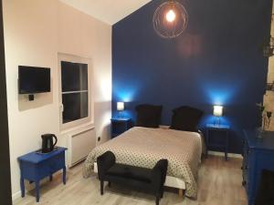 1 dormitorio azul con 1 cama y 2 mesas azules en le jardin de Camille en Tailleville