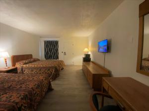 a hotel room with three beds and a television at Budget Inn New Cumberland-Harrisburg-Hershey-York in New Cumberland