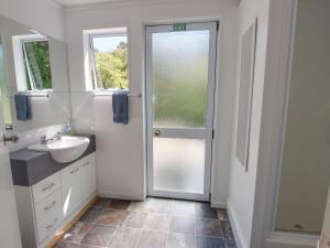 a bathroom with a sink and a glass door at Anakiwa 401 in Anakiwa