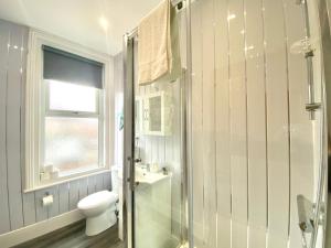 La salle de bains blanche est pourvue d'une douche et de toilettes. dans l'établissement Warley House 4 Bed -Blackpool North -Family House, à Blackpool