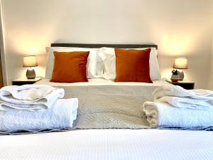 um quarto com uma cama com lençóis brancos e almofadas laranja em Warley House 4 Bed -Blackpool North -Family House em Blackpool