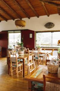 un restaurante con mesas y sillas de madera y ventanas en Sapê Guest Hotel, en Praia do Rosa