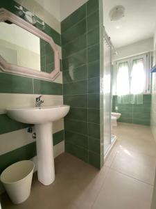 a green bathroom with a sink and a shower at Appartamento Guidetta 2 in Follonica