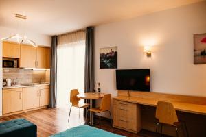 a living room with a kitchen with a table and a television at Tagore Spa Aparthotel in Balatonfüred