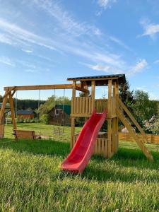 un parco giochi con scivolo rosso nell'erba di Žalioji stotelė butiko namukas dviems a Anykščiai