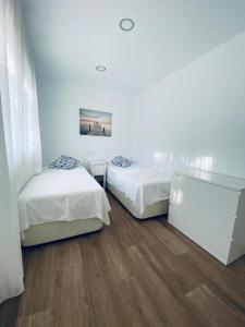 2 Betten in einem Zimmer mit weißen Wänden und Holzböden in der Unterkunft PRECIOSO APARTAMENTO EN EL TESORILLO in Almuñécar