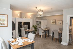 a dining room with tables and chairs and a kitchen at Bramwood Guest House in Pickering