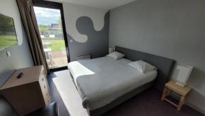 a bedroom with a large bed and a large window at Gold Beach Hotel & RESIDENCE in Asnelles
