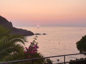 a sunset over the ocean with a ship in the water at Appartamenti Villa Lina - La Sorella in Nisporto
