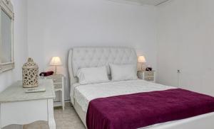 Un dormitorio blanco con una cama grande con una manta morada. en Villa Lemonia, en Glossa