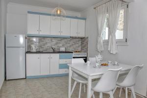 cocina con mesa blanca y armarios blancos en Villa Lemonia, en Glossa 18 fotos más