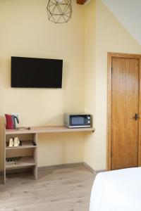 Zimmer mit einem TV an der Wand und einem Bett in der Unterkunft Timėjas in Ringaudai
