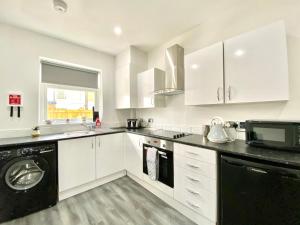 a kitchen with white cabinets and a black dishwasher at Warley House 4 Bed -Blackpool North -Family House in Blackpool