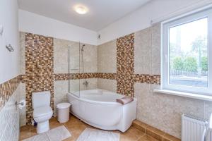 een badkamer met een bad, een toilet en een raam bij Vienības prospekts Apartment. in Jūrmala