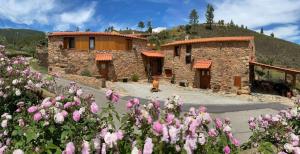 a building with a bunch of flowers in front of it at REFÚGIO DO RAPOSO/CASA VEGA in Montes da Senhora