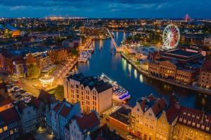 a city with a river and a ferris wheel at night at Old Town Apartment in Gdańsk