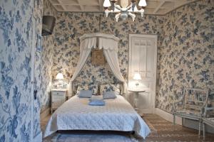 a bedroom with blue wallpaper and a bed with blue pillows at Château de Chantelauze in Olliergues