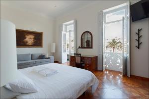 Santa Ana Suite & Rooms في لاس بالماس دي غران كاناريا: غرفة نوم بيضاء مع سرير وأريكة