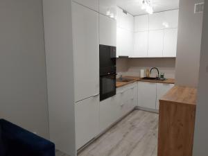 a white kitchen with white cabinets and a black oven at Holidays Home Ustrzyki in Ustrzyki Dolne