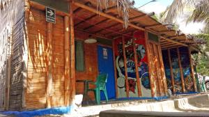 a wooden house with a green chair in front of it at Saigon Backpackers hostel in Máncora