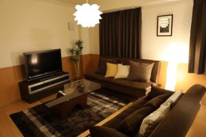 a living room with a couch and a tv at ケイアイコンホテルズ 新栄8階又は10階 in Nagoya