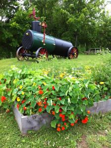 a flower garden in front of a planter with a tractor at Train Station Inn in Tatamagouche