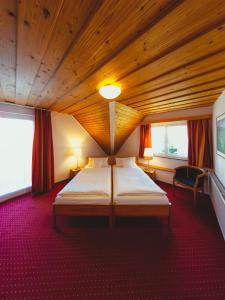 Hotel am Mühlbach في فورباخ: غرفة نوم بسرير كبير في سقف خشبي