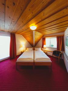 ein Schlafzimmer mit einem großen Bett in einer Holzdecke in der Unterkunft Hotel am Mühlbach in Forbach