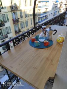 uma mesa de madeira com chávenas e uma chaleira de chá na varanda em Pretty and quiet top floor 2 bedroom flat in the port area of Nice em Nice