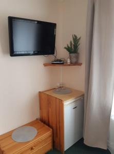 a room with a television on a wall with a wooden stand and a table at vila Happy in Veľká Lomnica