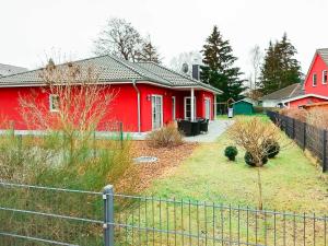uma casa vermelha com uma cerca em frente em Karlshagen Ferienhaus Sandy em Ostseebad Karlshagen