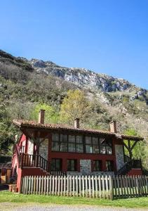 a house with a fence in front of a mountain at Les Vegues II in Santillán