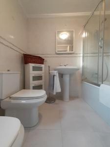 a white bathroom with a toilet and a sink at Vivienda Vacacional El Acebo - Cudillero in El Pito
