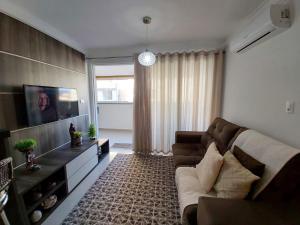 uma sala de estar com um sofá e uma televisão em A081 - Recanto do Cardeal Apto com 2 quartos - Bombas em Bombinhas