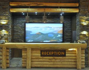 una TV a schermo piatto seduta sopra una parete di tronchi di Inan Kardesler Hotel a Uzungöl