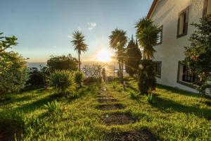 een pad dat leidt naar een huis met de zon op de achtergrond bij Secluded Sunset Villa on Cliff & 180 Degree Ocean Views in Fajã da Ovelha