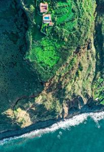 eine Luftansicht eines Hauses auf einer Klippe neben dem Meer in der Unterkunft Secluded Sunset Villa on Cliff & 180 Degree Ocean Views in Fajã da Ovelha