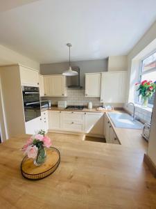 a kitchen with white cabinets and a table with flowers on it at Acacia Breezes - Delightful Scarborough Semi in Scarborough