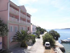 a building with a car parked next to the water at Apartments Svetka - 10m from the sea in Sali