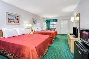 a hotel room with two beds and a flat screen tv at Travelodge by Wyndham Suites St Augustine in St. Augustine