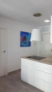 a kitchen with white cabinets and a blue painting at Malagueta & Port in Málaga +11 photos