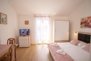una camera da letto con un letto, un tavolo e una televisione di Bol apartments Gospojica a Bol