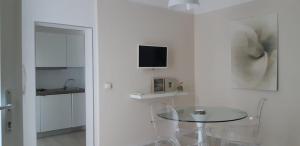 um quarto branco com uma mesa de vidro e uma televisão em La Vela em Castro di Lecce